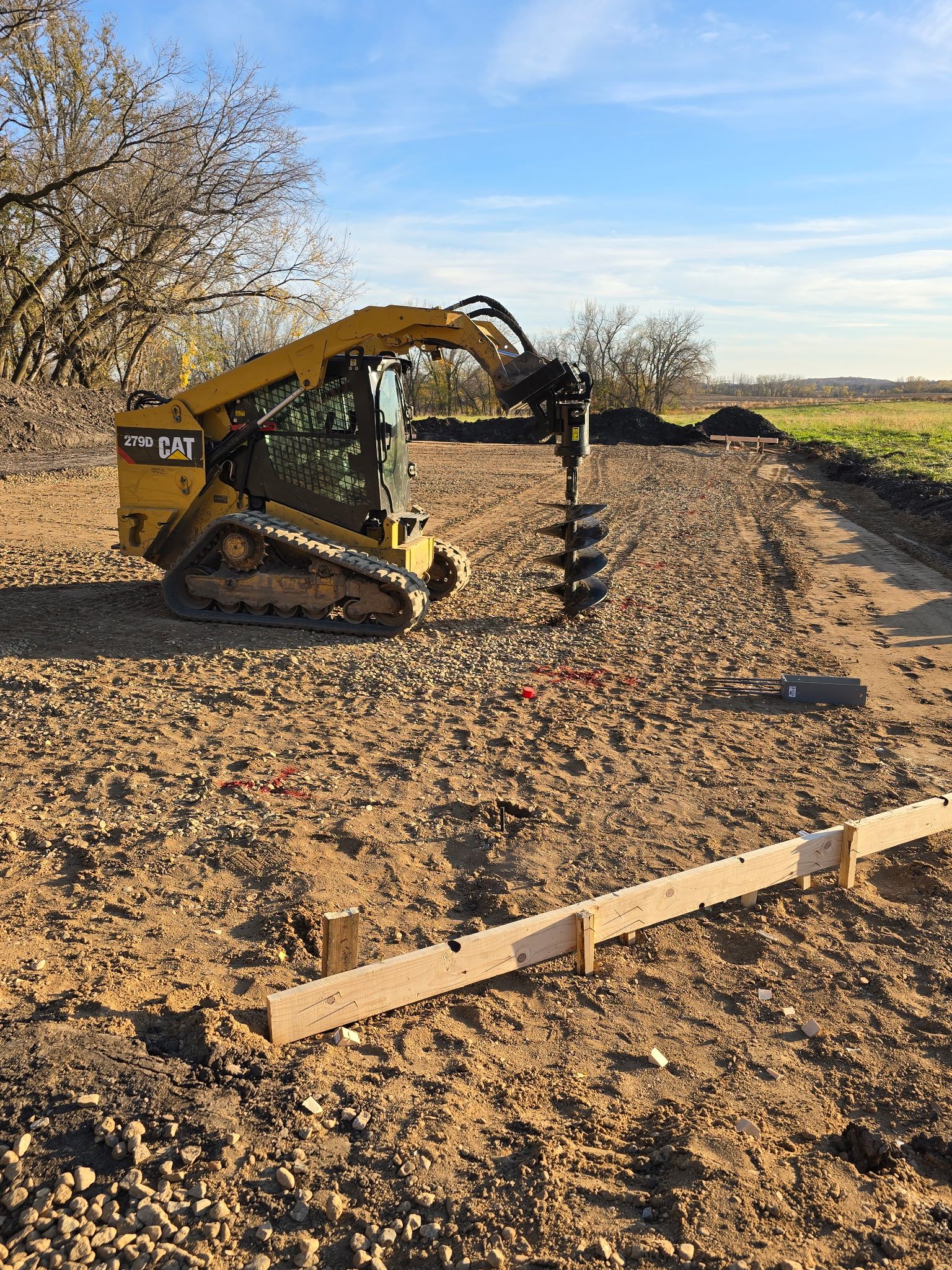 Skid steer drilling post holes for a pole barn foundation