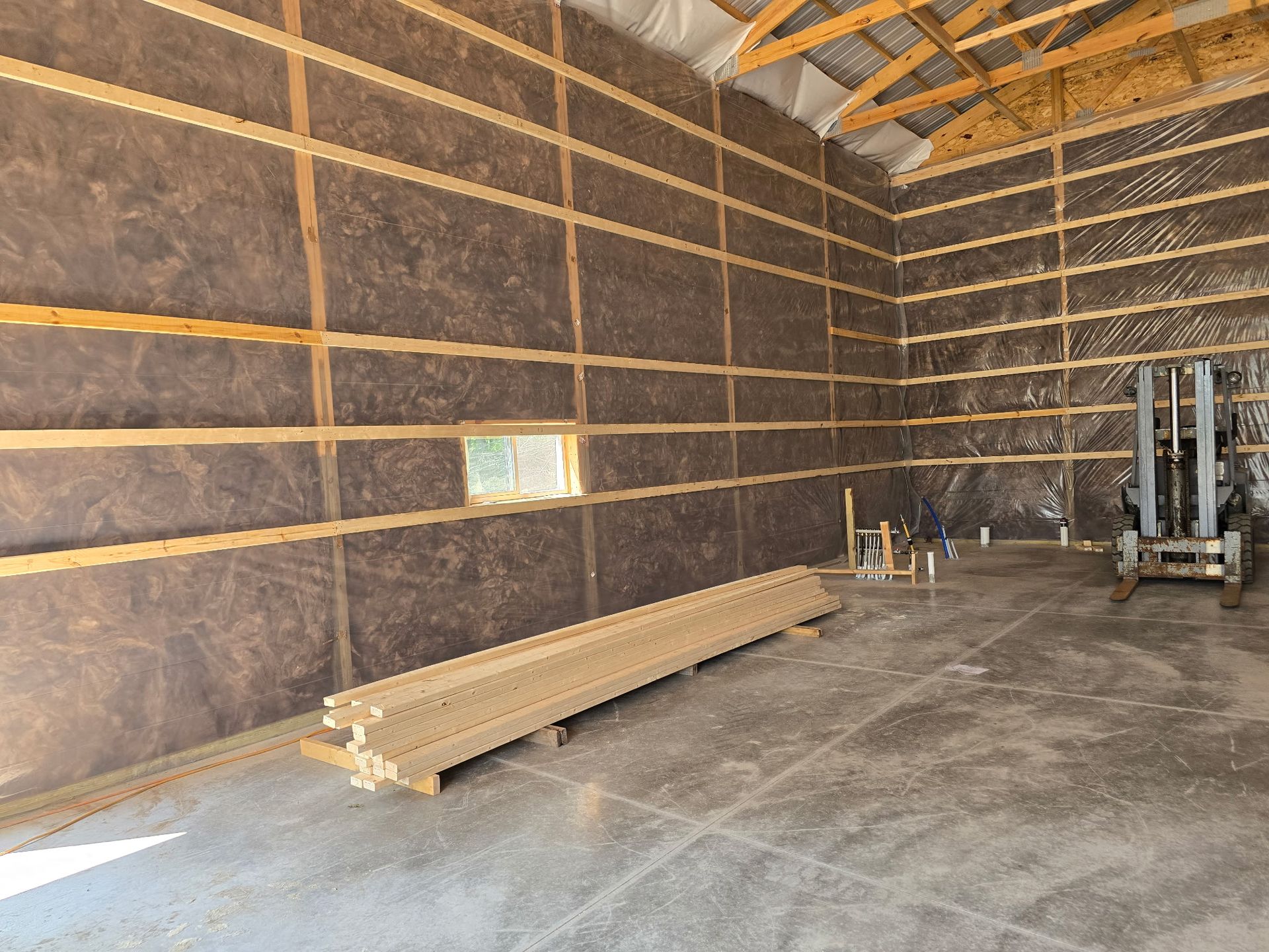 Insulated interior of a large commercial building with concrete floor and exposed roof trusses
