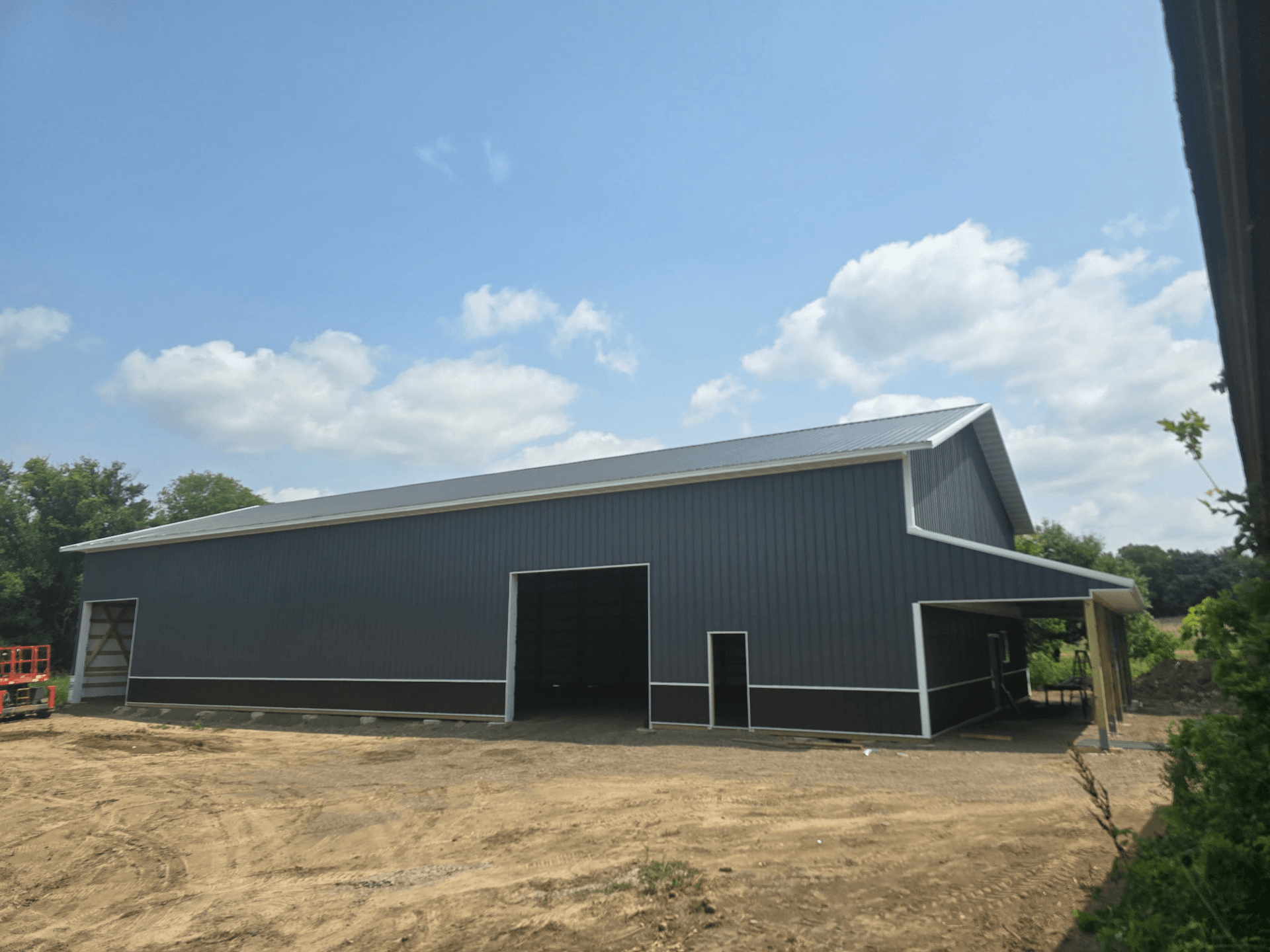Building with charcoal siding, stone veneer, white trim, and concrete driveway